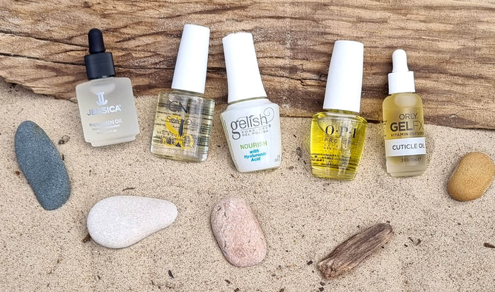 A collection of cuticle oils displayed in an aesthetically pleasing arrangement, featuring CND SolarOil, OPI Pro SPA Nail & Cuticle Oil, Gelish Nourish Cuticle Oil with Hyaluronic Acid, Jessica Phenomen Cuticle Oil, and ORLY Gel FX Cuticle Oil.